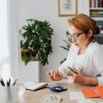 Woman Sitting at Desk Counting Money